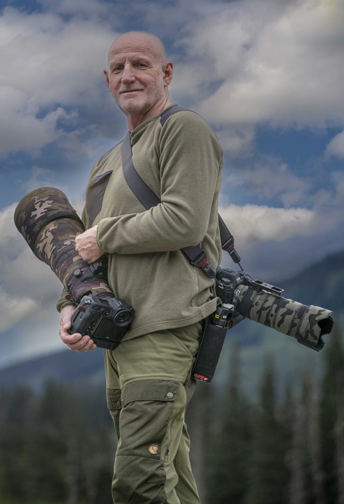 Le photographe voyageur Gilles Thomas portant son équipement photo en extérieur.